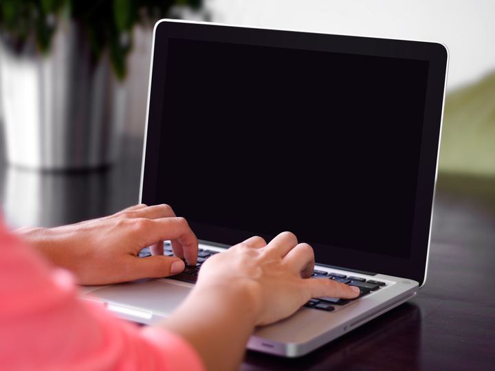 Hands typing on a laptop keyboard